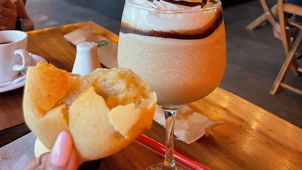 Une boisson dessert à la crème fouettée et au sirop de chocolat, une pâtisserie à moitié mangée et une tasse de café sur un plateau.