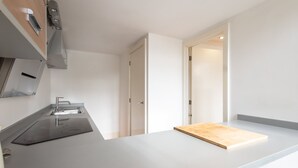 A modern kitchen with a built-in stove, a sink, and a wooden cutting board on the counter. - Host Stay City Hall View (Sheffield)