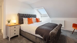 Une chambre à coucher avec un lit, une table de chevet, une chaise et une lucarne.