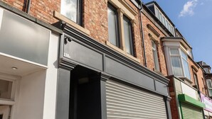 Une rangée d’immeubles en briques, avec un commerce au rez-de-chaussée.
