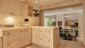 A modern kitchen with wooden cabinets, a central island, and a dining area with green chairs. - w Fantastic House w Amazing Pool in Cartagena (Cartagena)
