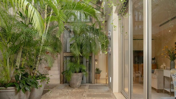 A corridor with potted plants, a stone-tiled floor, and a glass door leading to a room with a bed and a nightstand. - w Fantastic House w Amazing Pool in Cartagena (Cartagena)