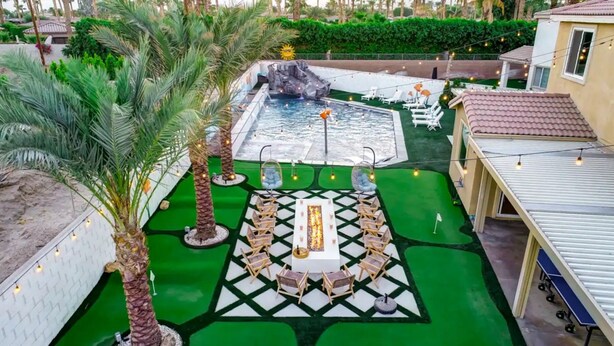 Zona de piscina con jacuzzi, sillones de descanso y un pequeño escenario con mesa y sillas.