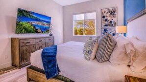 A bedroom with a large bed, a TV mounted on the wall, a window, and artwork on the wall. - The Royal Bahamian- Pickleball Golf Sleeps 20 (Indio)