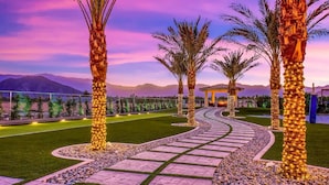 A landscaped pathway with palm trees and a gazebo, surrounded by a fence and mountains in the background. - The Royal Bahamian- Pickleball Golf Sleeps 20 (Indio)