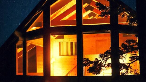 Ett modernt hus med flera våningar, stora fönster och en varm och inbjudande atmosfär.