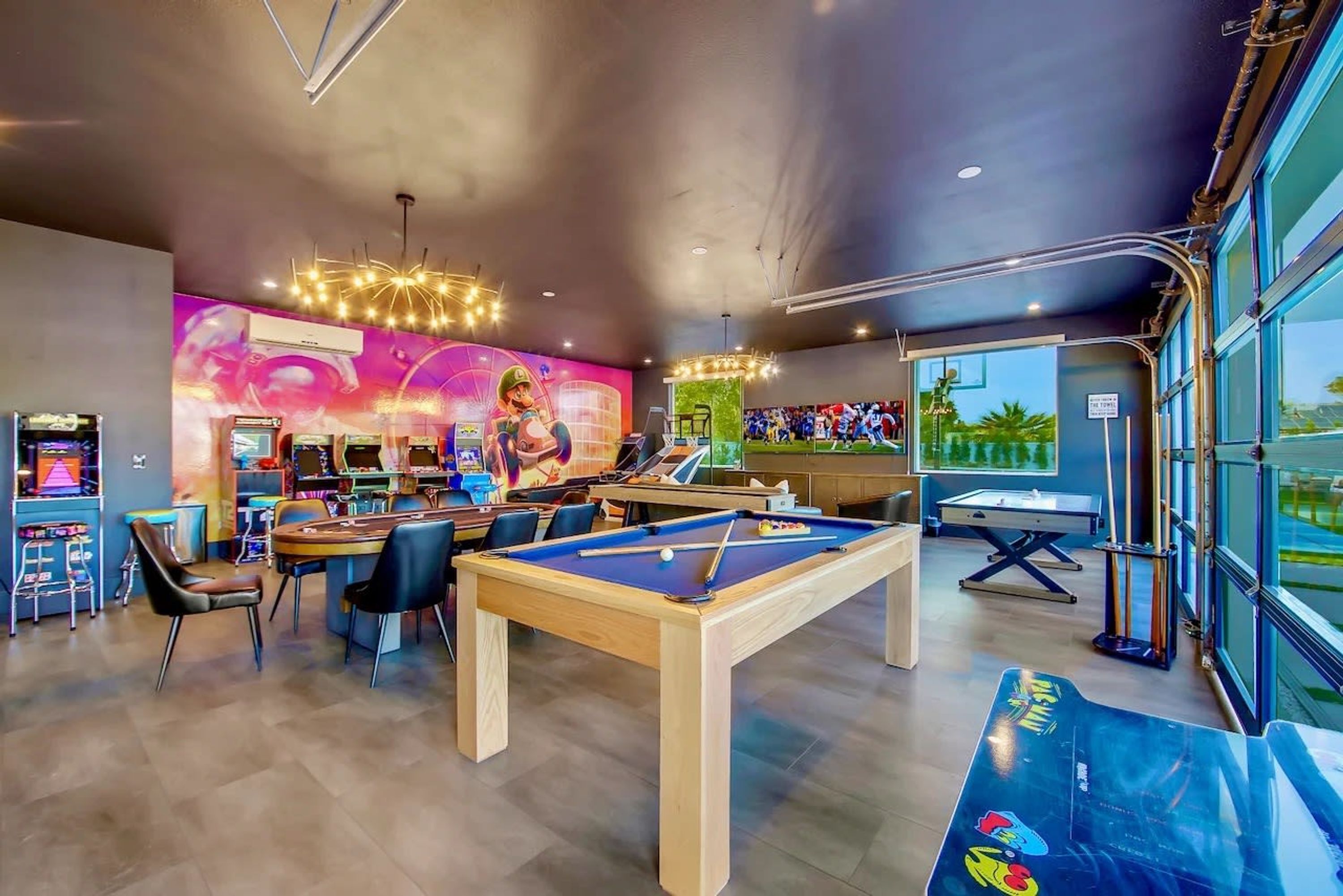 Una sala giochi con diversi tavoli da biliardo, un tavolo da snooker e un murale illuminato al neon.