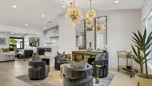 A modern living room with a large mirror, round black ottomans, and a gold-framed mirror.