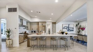 A modern kitchen with a large island, bar stools, and a dining area with chairs.
