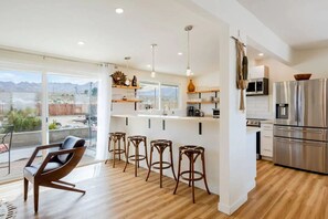 Une cuisine moderne avec un coin bar, de grandes fenêtres et une vue sur les montagnes.