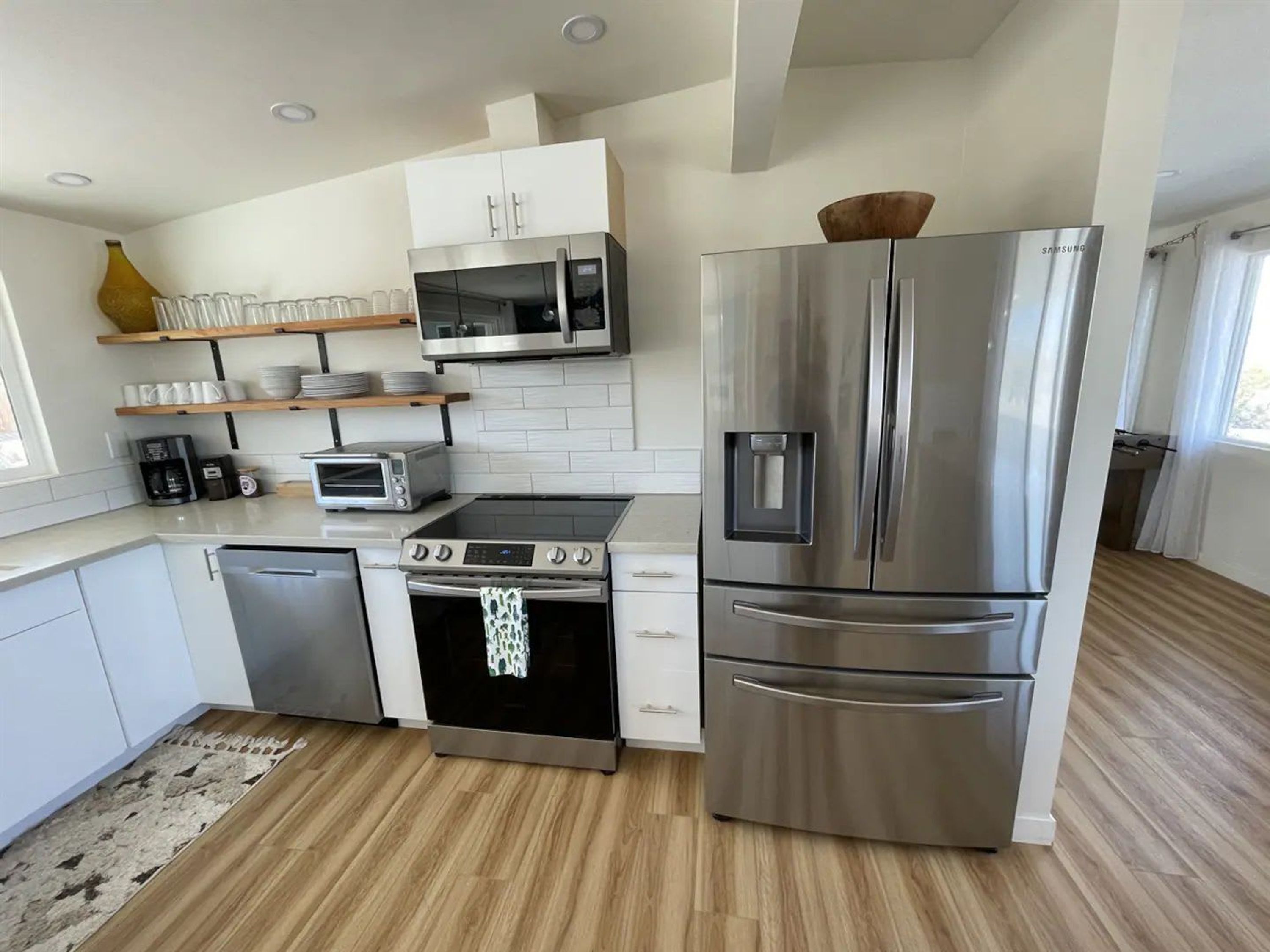 Una cocina moderna con electrodomésticos de acero inoxidable, microondas, tostadora y refrigerador.