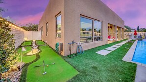 Ein modernes Haus mit Swimmingpool, einem gepflegten Rasen und einem kleinen Putting-Green.