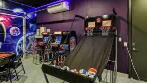 Ein Zimmer mit Basketballkorb, Spielautomaten und einer Wand zum Thema Weltraum.