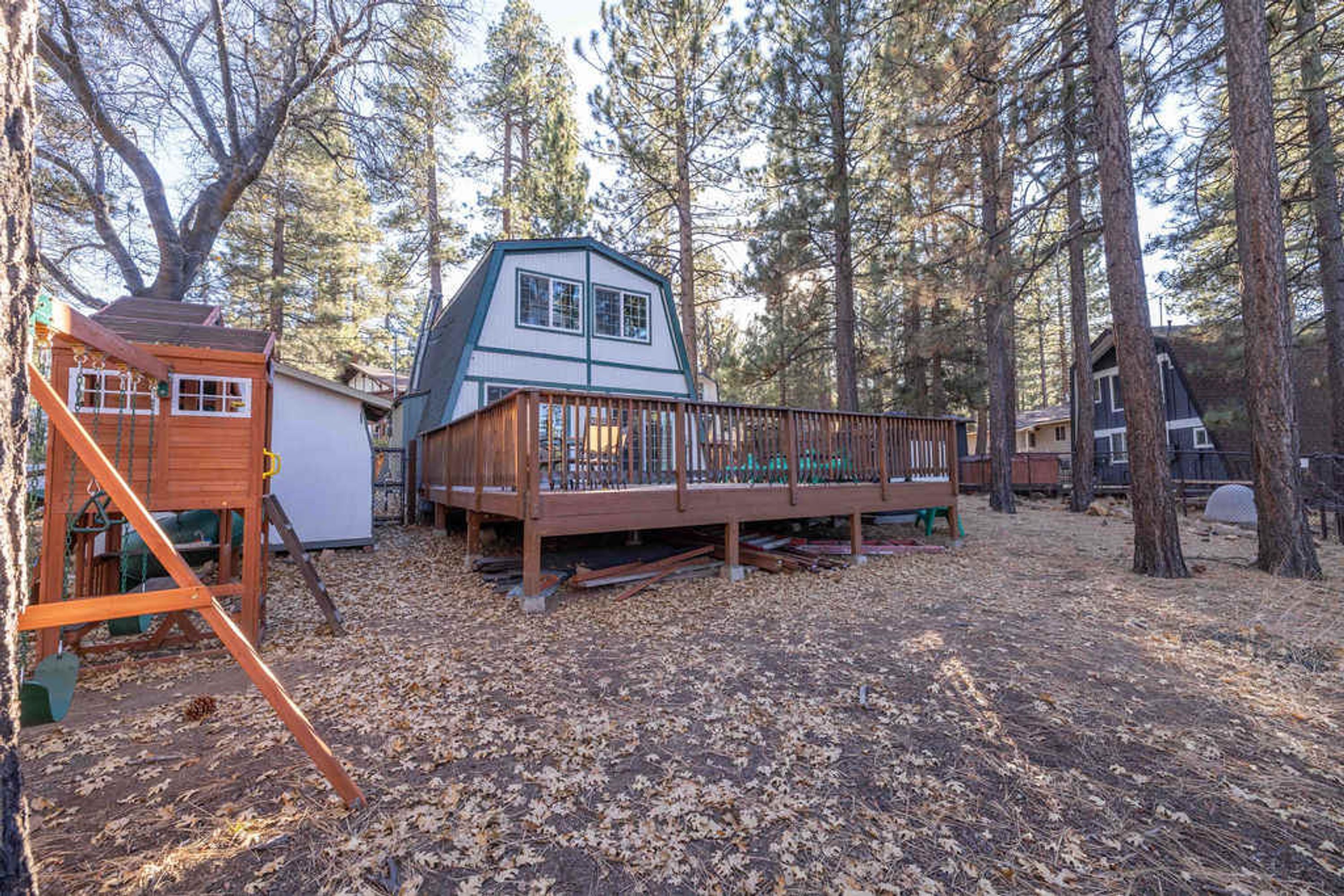 A cabin with a wooden deck, surrounded by trees.