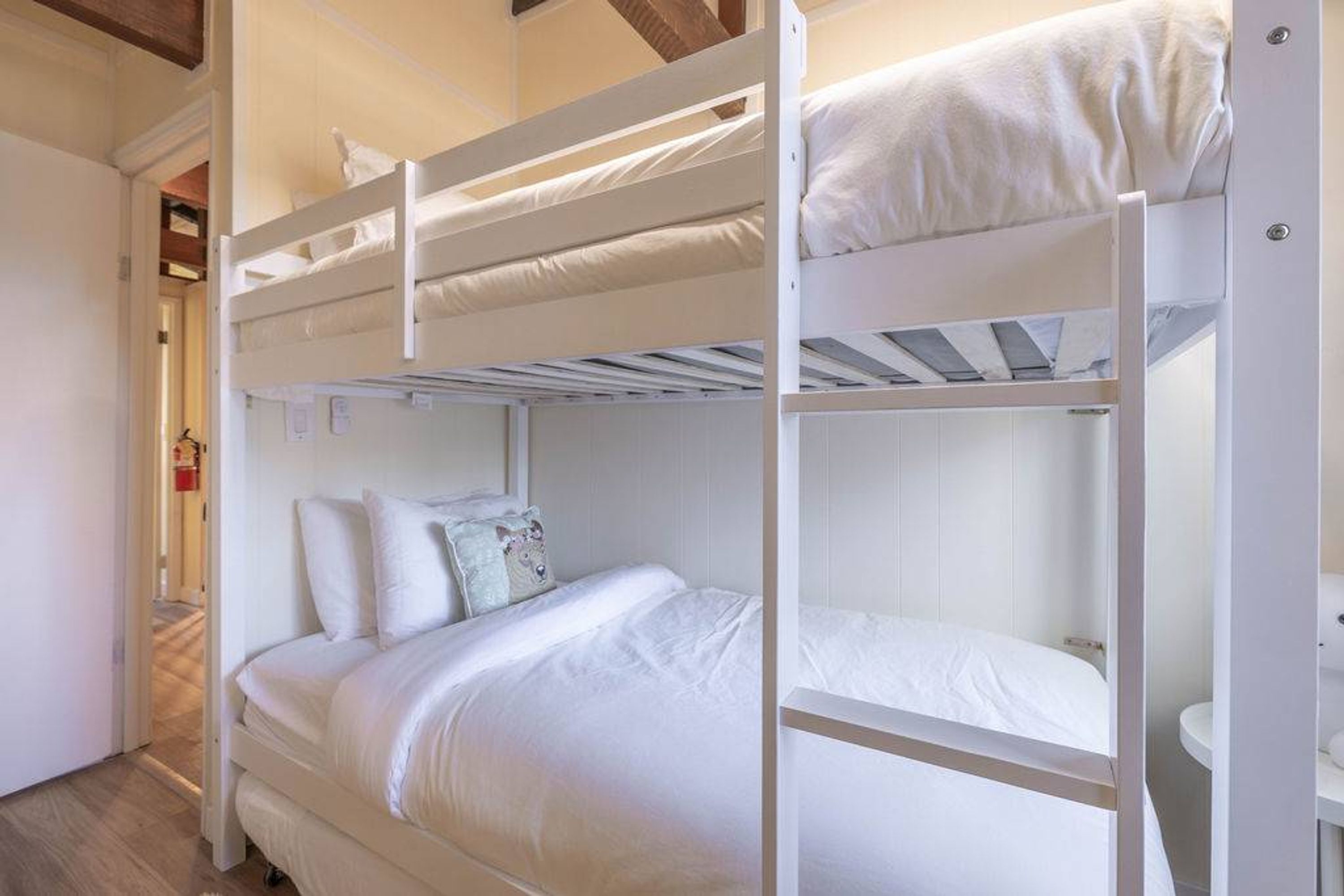 Ein Schlafzimmer mit Etagenbetten, weißer Bettwäsche und einem kleinen Nachttisch.