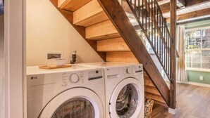 Un área de lavandería con dos lavadoras LG, una escalera de madera y vistas al exterior.