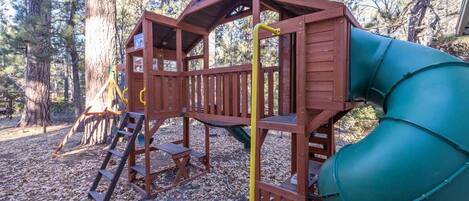 A wooden play structure with a slide and a ladder.
