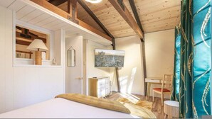 Un dormitorio con una cama, un escritorio, una silla, un espejo y un cuadro en la pared.