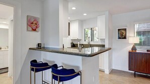 Una cocina moderna con una isla central, taburetes de bar y un comedor con mesa y sillas.