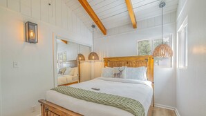 Una camera da letto con un letto in legno, una coperta lavorata a maglia verde e due lampade a sospensione.