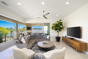 Een moderne woonkamer met een modulaire bank, een ronde salontafel en een flatscreen televisie op een houten dressoir.