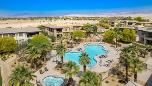 Un resort con una amplia piscina rodeada de palmeras y sillas de descanso.