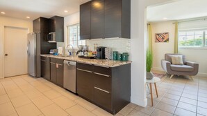Una cocina moderna con armarios oscuros, un refrigerador de acero inoxidable, un microondas y una cafetera.