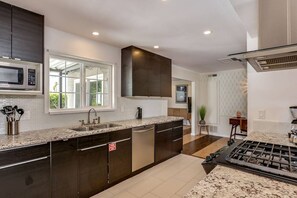 A modern kitchen with dark cabinetry, a stainless steel dishwasher, a built-in microwave, and a gas stove. - Relax at the 3BR Tranquil Oasis in Palm Springs (Palm Springs)