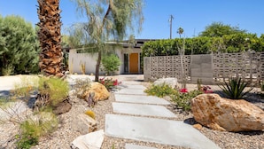 A pathway leading to a house with a modern design, surrounded by various plants and rocks. - Lux Desert Retreat 4BR Pool Spa Stunning Views (Palm Springs)
