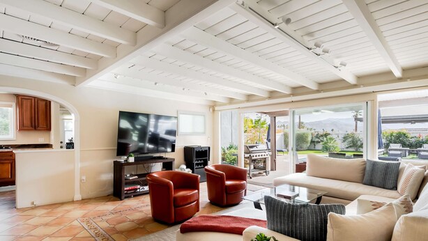A spacious living room with a large TV, comfortable seating, and a view of the outdoors. - Movie Colony Oasis - Peaceful Walk to Downtown (Palm Springs)