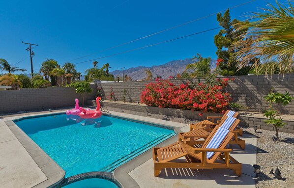 A swimming pool with lounge chairs and a pink flamingo float. - Modern Home w Private Pool Spa Pets Welcome (Palm Springs)