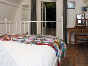 Cozy retreat with a comfortable bed, desk, and window view of lush greenery.
