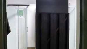 A room with a glass door leading to a shower area, a black piece of furniture, and a white wall. - BALLYBEG POD 4, romantic, with hot tub in Tinahely, County Wicklow (Arklow)