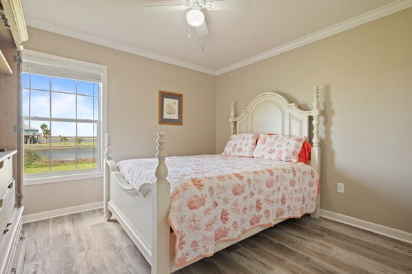 A bedroom with a bed, a window with a view, and a ceiling fan. - Blue Lagoon - Super cute, water/bay view, close to beach and bay! (Port Bolivar)