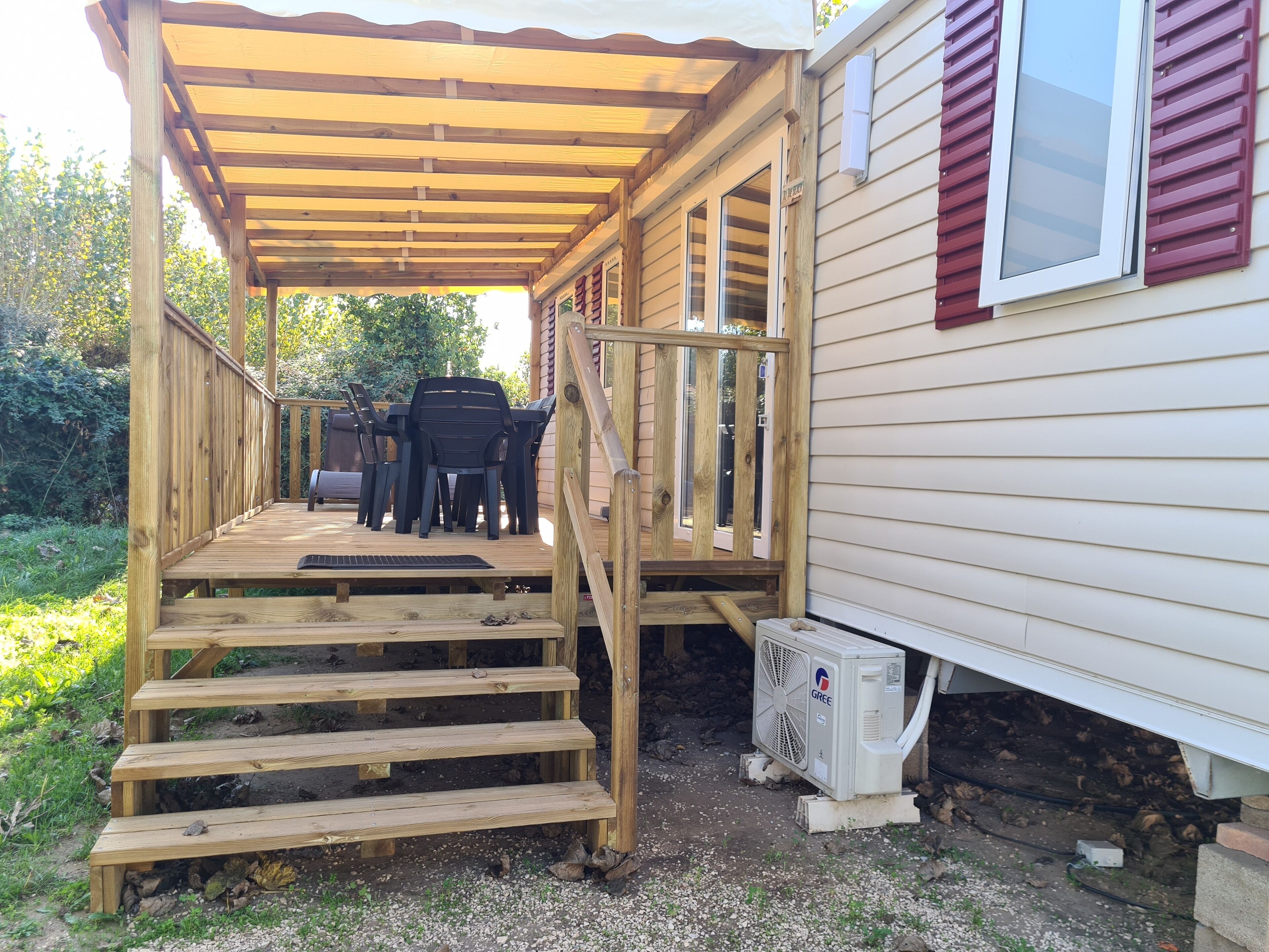 A wooden deck with outdoor seating, a covered porch, and a visible air conditioning unit.