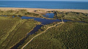 An aerial view of a coastal area with a beach, water bodies, and dense vegetation. - CAP VALRAS Les sables du midi (Valras-Plage)