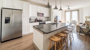 Una cocina moderna con una isla central, electrodomésticos de acero inoxidable y taburetes de madera.