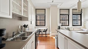 A modern kitchen with white cabinetry, a built-in stove, and a dining area with a table and chairs.