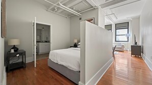 A modern bedroom with a bed, bedside tables, a wardrobe, and a bathroom visible through an open door.