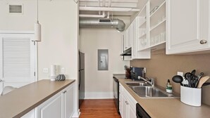 A modern kitchen with white cabinetry, stainless steel appliances, and a wooden floor.