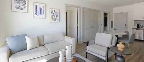 A modern living room with a sofa, armchairs, a coffee table, and artwork on the wall.