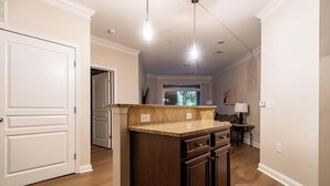 A kitchen with wooden cabinets, a granite countertop, and pendant lighting. - Landing | Modern 1BD, Courtyard, Gym (Cary)