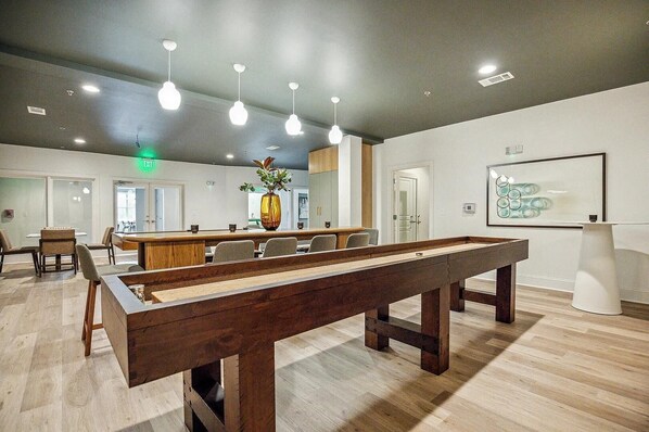 A billiards table in a modern room with wooden flooring, recessed lighting, and a minimalist decor. - Landing | Incredible 2BD, Gym, Pool (Cary)