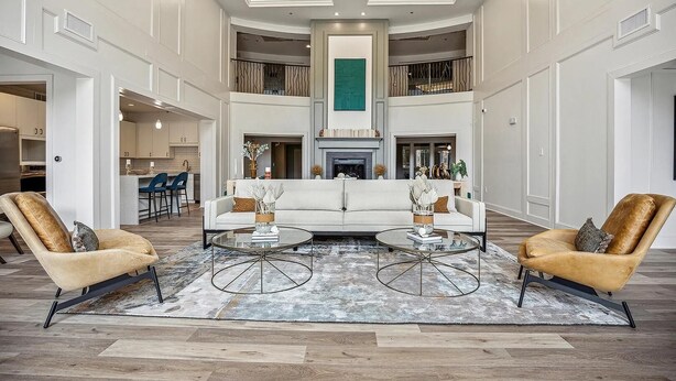 A spacious living area with a central white sofa, two armchairs, and a fireplace. - Landing | Modern 2BD, Pool, Rooftop Lounge (Cary)