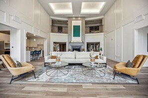 A spacious living area with a central white sofa, two armchairs, and a fireplace. - Landing | Incredible 2BD, Gym, Pool (Cary)