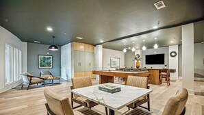 A modern living room with a dining area, a kitchen, and a bar area. - Landing | Modern 2BD, Pool, Rooftop Lounge (Cary)