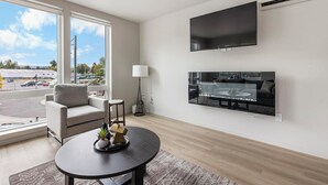A modern living room with a sofa, a coffee table, and a TV mounted on the wall. - Landing | Amazing 2BD, Gym, Pool (Portland)