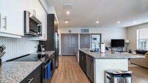 A modern kitchen with granite countertops, stainless steel appliances, and a central island. - Landing | Beautiful 2BD, Gym, Clubhouse (McKinney)