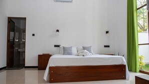 Une chambre à coucher avec un lit en bois, du linge de lit blanc, deux tables de chevet et un rideau vert.