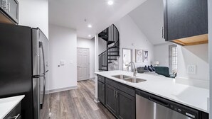 A modern kitchen with a stainless steel refrigerator, a dishwasher, and a white countertop. - Landing | Stylish 2BD, Pool, Clubhouse (Cincinnati)